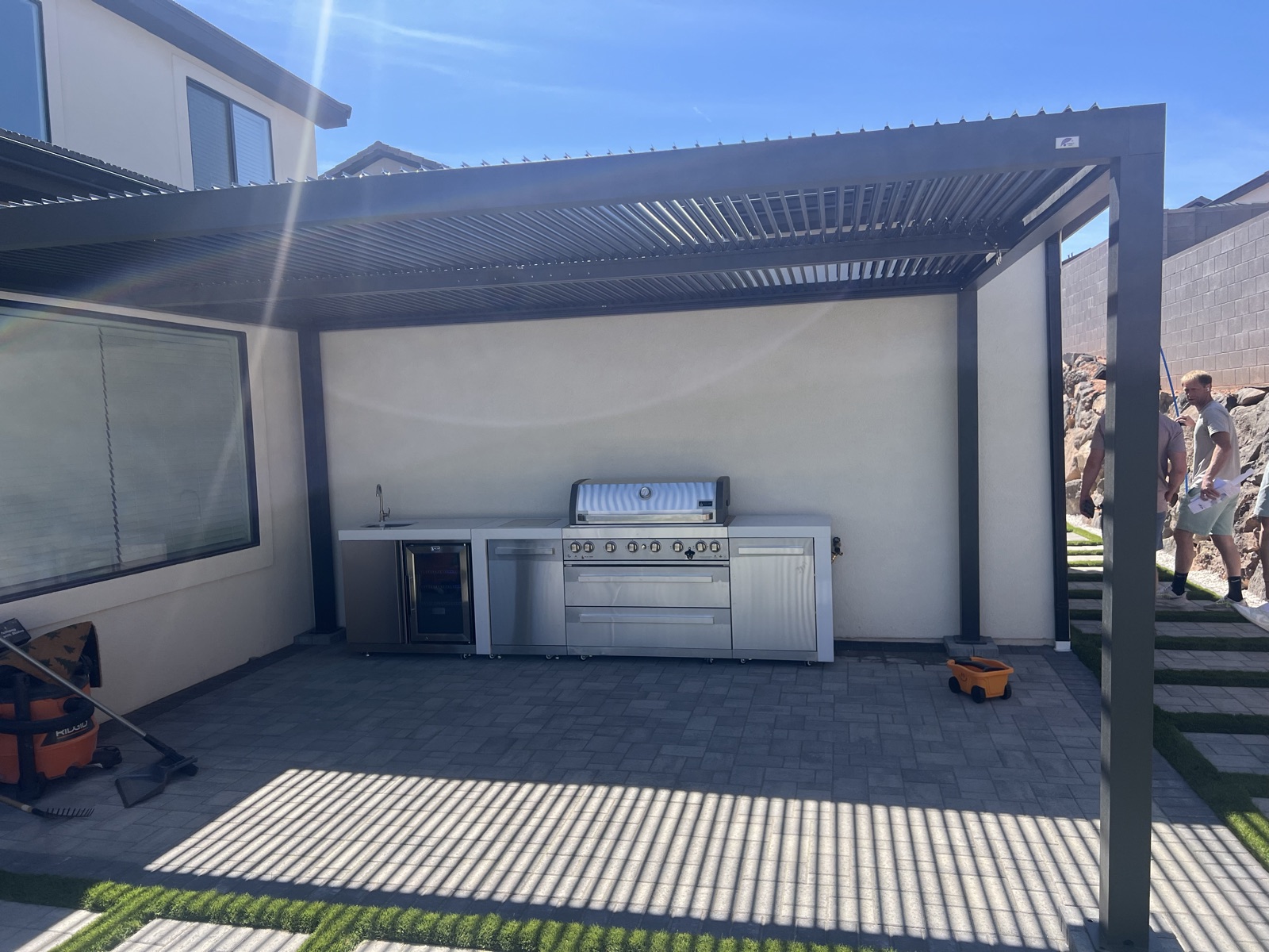 Outdoor kitchen with louvered pergola and paver patio — Sol Scapes Utah