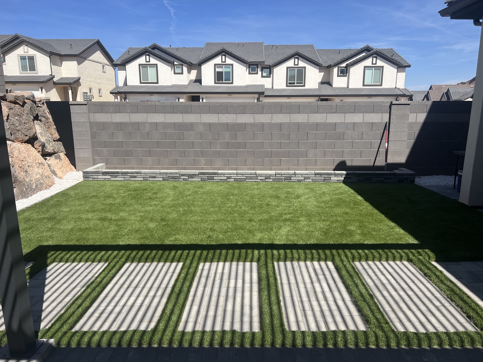 Backyard artificial turf with block retaining wall and pavers — Sol Scapes Utah